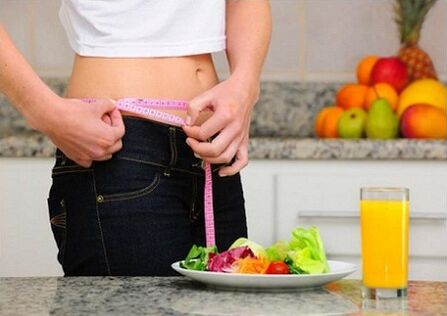A girl on a diet measures her waist